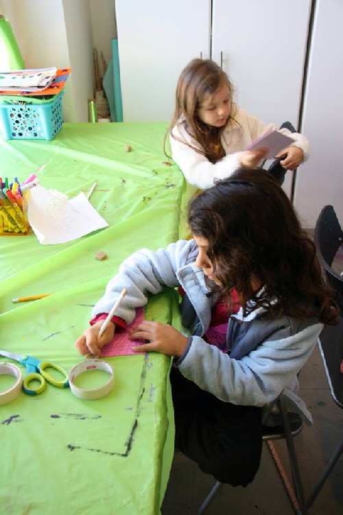 Samantha, 6, and Arielle, 5, simultaneously pencil out design for their respective printmaking projects. 