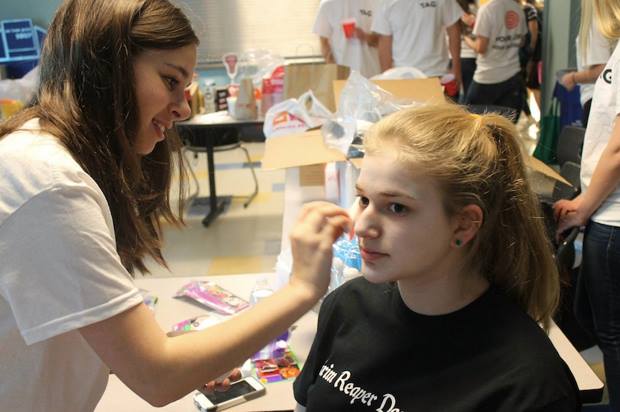 Isabel Perry ’15, a member of TAG, puts makeup on victim Carly Singer ’14. 