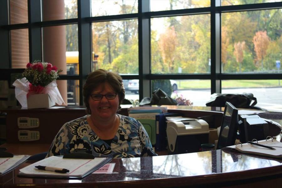 McQuone smiles from her  desk, greeting students on their way into school.  