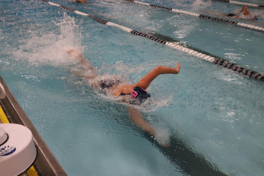 A swimmer on the Staples girls’ swim and dive team is racing as fast as she can in order to try and win her event. She is focusing on her technique and energy, not the possibility of her swimsuit shifting around in the water.