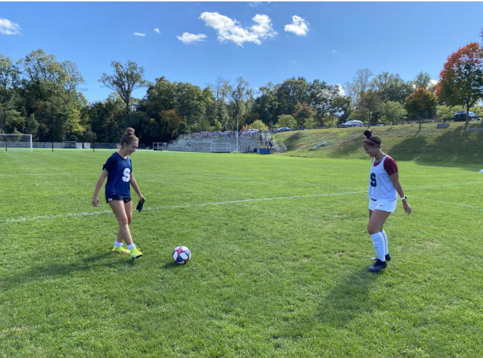 Arden Scherer and Charlotte Zhang warming up before soccer practice. 
