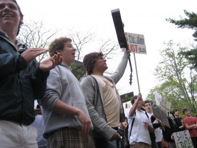Alex Shmerzler '10 raises his guitar in protest as others raise their signs at the rally. Photo by Ross Gordon