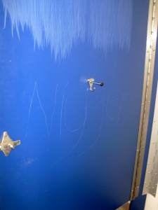 The inside of a bathroom stall door reads "n****r." Photo by Ted Swanson '83