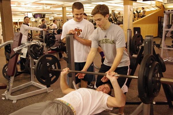 A Word in Edge-Wise: (Top) Spencer Adler ’11 spots Jordan Goldstein ’11 as he bench presses 195 pounds and Steven Denowitz ’11 provides encouragment.