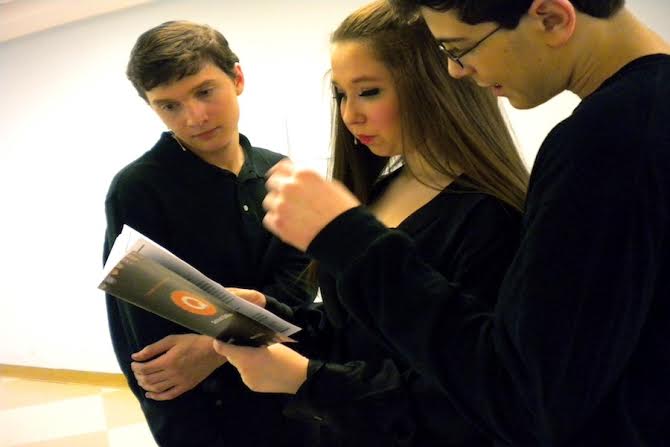 Zoe Fox ’16, who played Care-ee bear, Garrick New’16, who played Pooh, and Aaron Samuels ’16, who played Paddington, look through the playbill for their names and ads during a break. 
