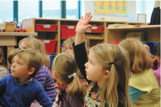 Miss Linda describes the activities for the day to her engaged audience in the classroom.