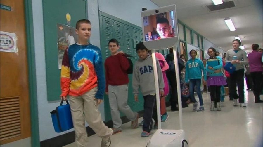 Students walk in hallways to get to class as usual, while their peer who was out sick is wheeled around on a rolling screen. This student was able to keep up in class and is another futuristic alternative to keep kids up to date when they have to miss class.
