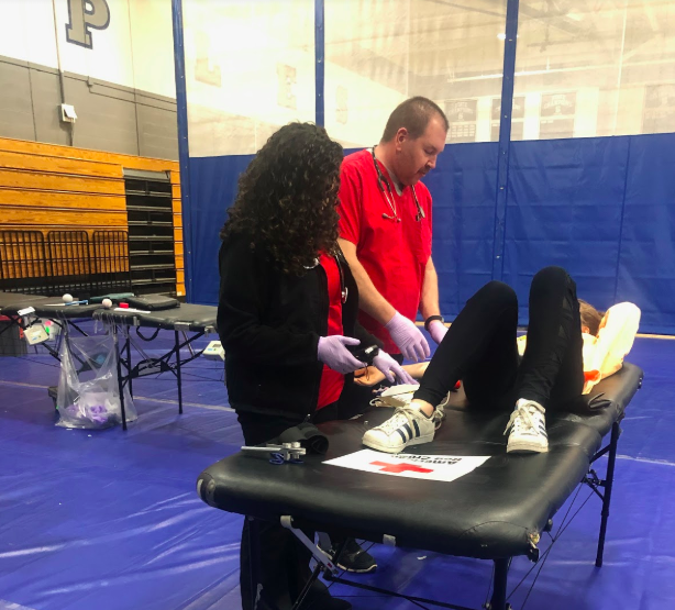 Phlebotomists from the Red Cross take blood from one of the 29 Staples student volunteers.