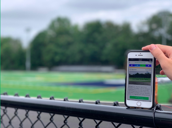 Student checks out the recently created field petition with 1,106 signatures, in front of the newly finished field, with no track. 