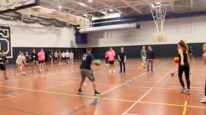 A police officer participating on a student team goes to throw the dodge ball after the game started. 
