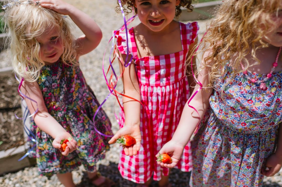 Three little ones show off freshly picked strawberries from the farm.