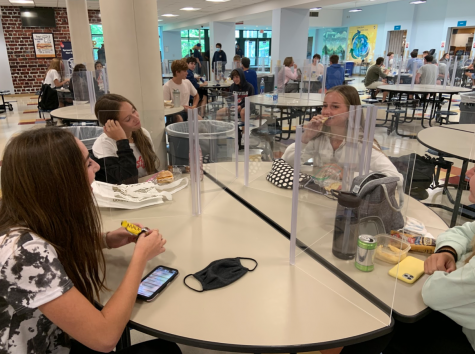 Alex Gordon ’24, Ruby Kantor ’24 and Alice Anderson ’24 eat lunch with the new dividers to accommodate for school with COVID-19. With the new regulations, students must sit three or four to a table, with X’s on every other seat. 