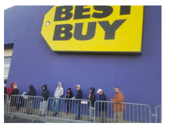 Black Friday, 2019. Customers line up outside Best Buy, waiting for the doors to open. Sales include items such as phones, headphones, cameras and computers. 