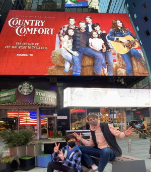 (L-R), Cast members Griffin McIntyre and Jamie Mann ’21 pose in front of the “Country Comfort” billboard in Times Square, New York City.