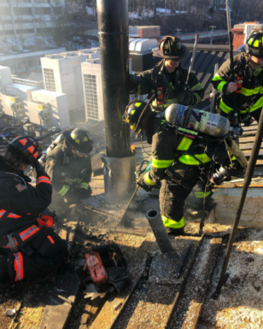 Firefighters work to extinguish the blaze, which originated under the roof’s sheathing, on top of the National Hall building in Westport. Westport and Norwalk departments collaborated on this effort.