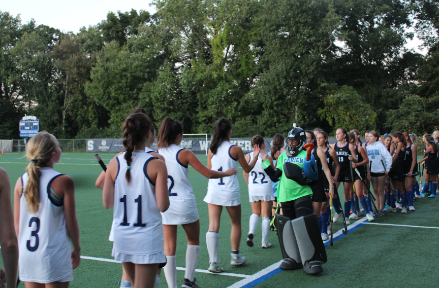 Staples and Darien show good sportsmanship by high-fiving each other after the game ends. 