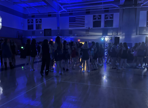 Inside the gymnasium students dance to music played by a DJ. Students are here for the majority of the night. 