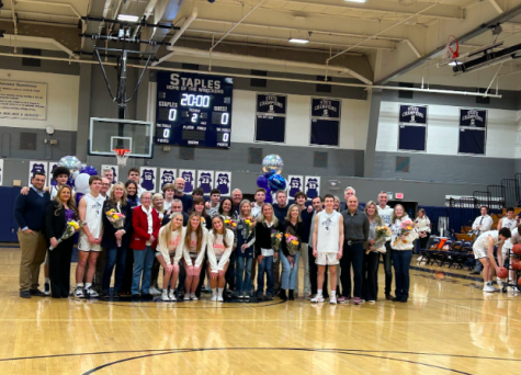 The senior basketball players and senior cheerleaders pose with their parents after the senior award ceremony prior to the start of the game.