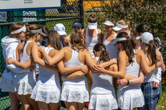 The girls’ tennis team comes together for a pre-match team huddle at home. 