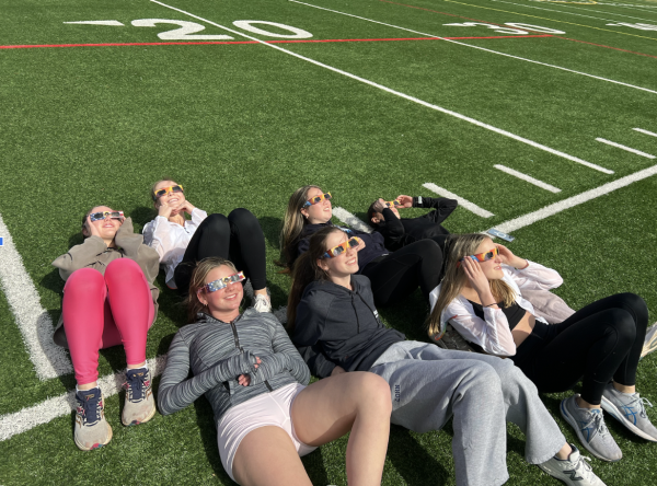 Staples girls track watches the eclipse using their glasses before they start practice. 
