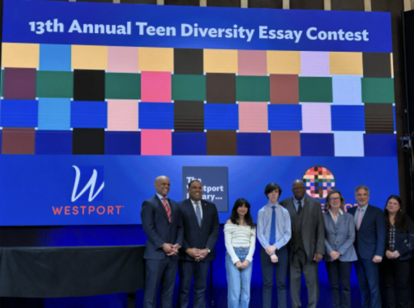 TEAM Westport members and Westport figures stand with the winners of the contest, left to right: 1st Selectman Kevin Christie, Principal Stafford Thomas, Kaila Patel ’27, Liam Harrison ’28, TEAM Westport chair Harold Bailey, essay contest chair Maggie Mudd, Westport Library director Bill Harmer, judge Michelle Rubin.