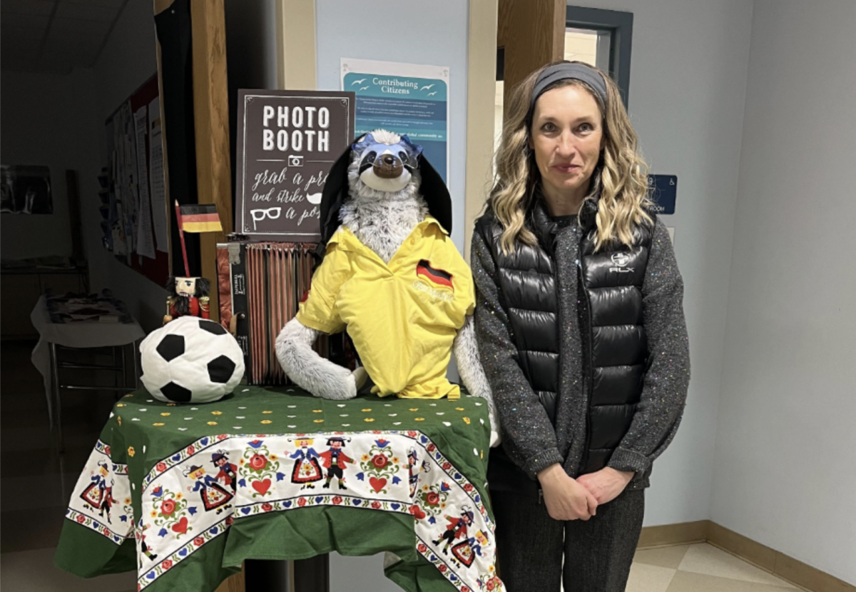 German Teacher Liubov Ulianova poses in front of her German classroom with a table decorated with symbols of German culture and photo booth props that invited students to pose for photos throughout the day and recognize the German language and culture. Photo from Staples girls' basketball website.